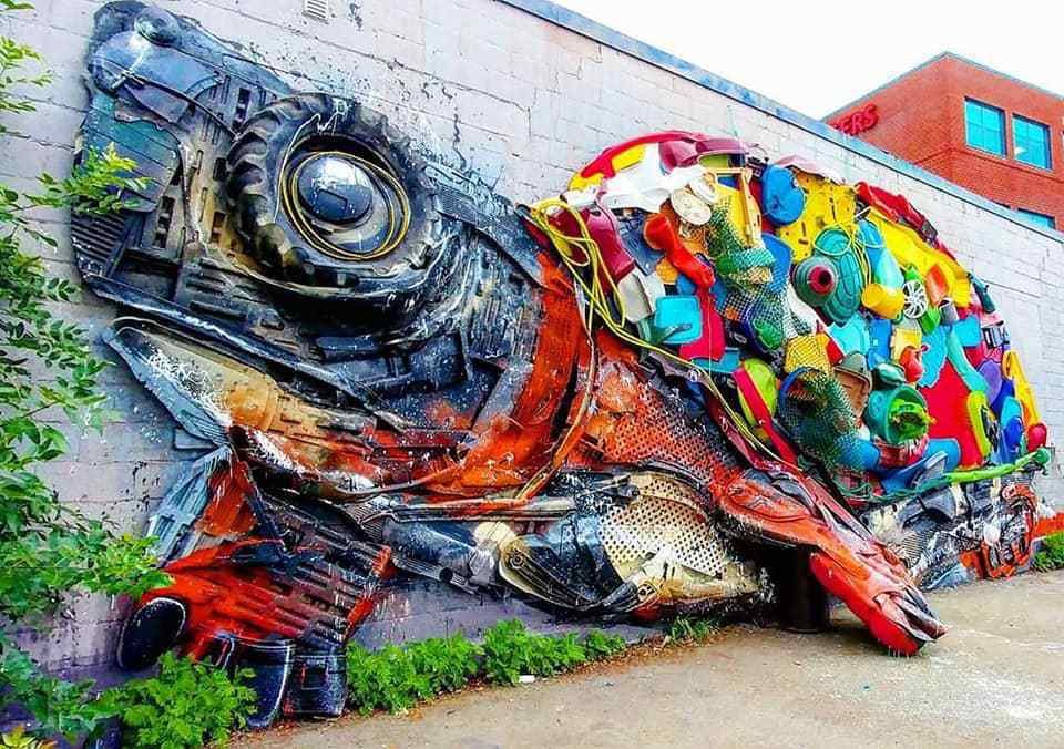 Tartaruga gigante feita de resíduos coloridos encostada a uma parede