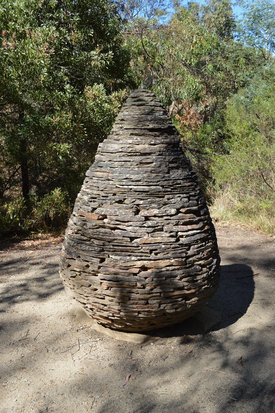 Cone de lascas de ardósia empilhadas, em forma de ovo, num terreno com árvores