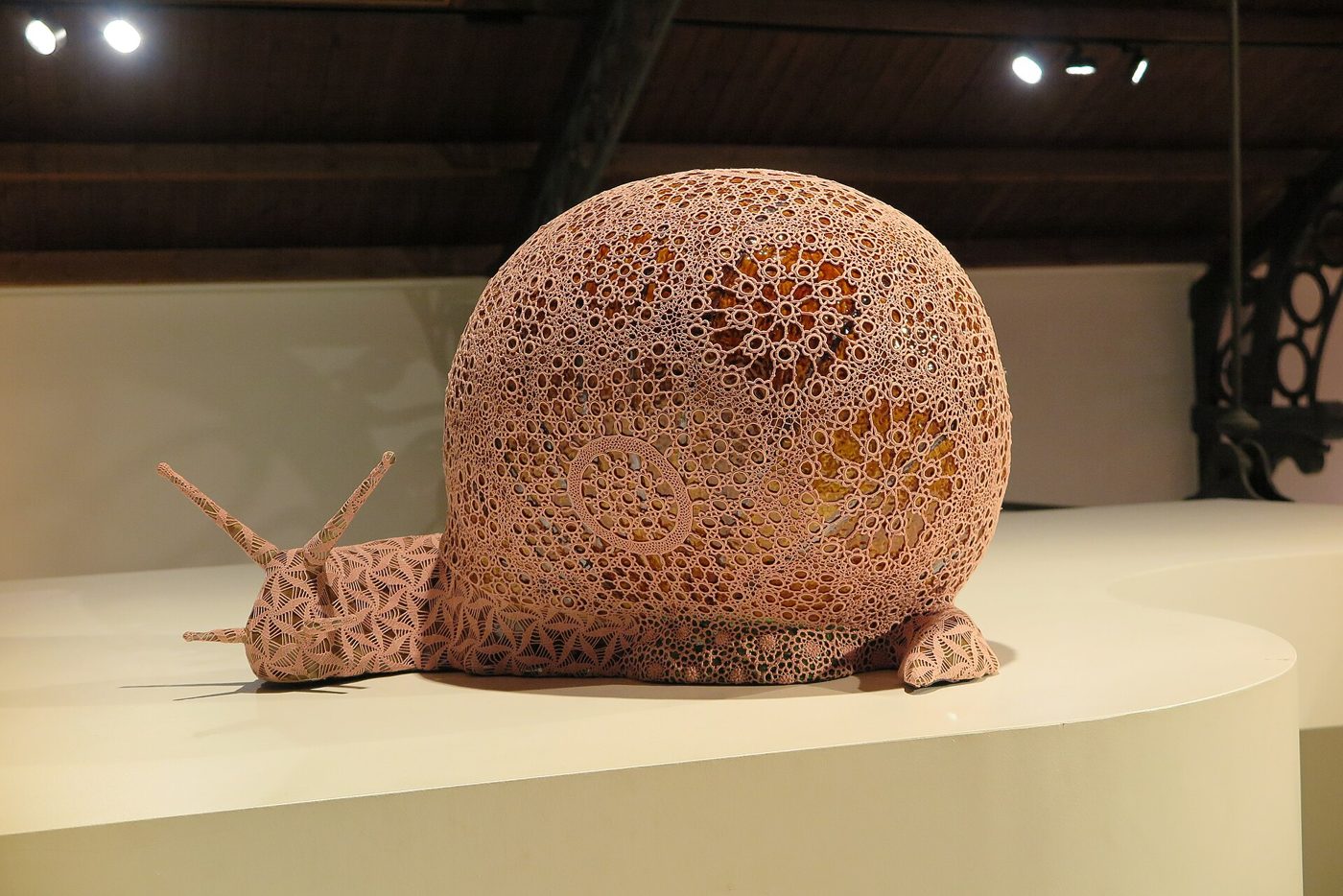 Caracol de cerâmica em tamanho gigante, coberto por uma renda de croché cor-de-rosa